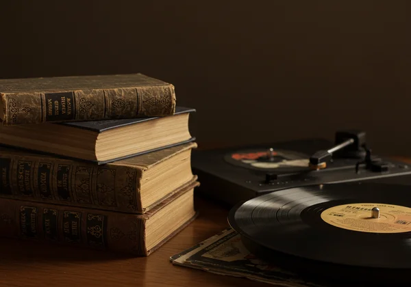 A stack of classic novels next to a vintage record player.